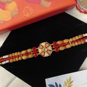Alt Text: Rakhi with wooden beads, red thread, central motif, and festive box including Chandan Tilak, handkerchief, and personalized card.