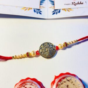 Golden Peacock Rakhi with red thread, golden beads, Sparsh greeting card and roli chawal set for Raksha Bandhan